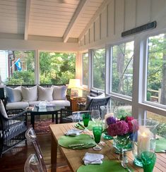 a dining room table set with place settings and flowers on the table, in front of large windows