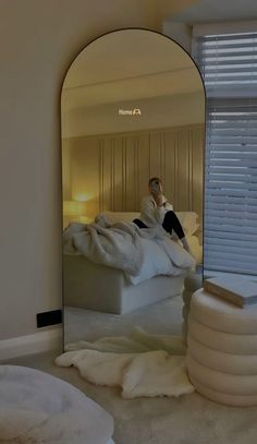 a person sitting on a bed in front of a mirror