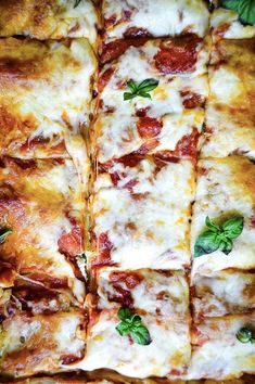 a square pizza with cheese, sauce and basil leaves on it's crusts