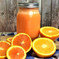 some oranges are sitting on a wooden table next to a jar of orange juice