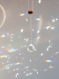 a wind chime hanging from a string with bubbles in the air and rainbows behind it