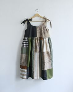 a dress hanging on a white wall with a black bow at the neck and two different colors