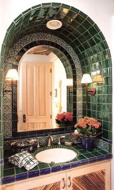 a bathroom with green and blue tiles on the wall, sink and mirror in it