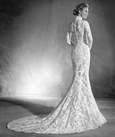 a black and white photo of a woman in a long sleeved wedding dress with an open back