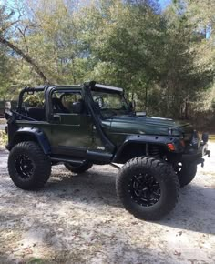 a green jeep parked on top of a dirt field