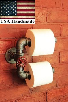 two rolls of toilet paper hanging on a brick wall with an american flag in the background