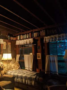 a living room filled with furniture and bookshelves next to a window covered in curtains