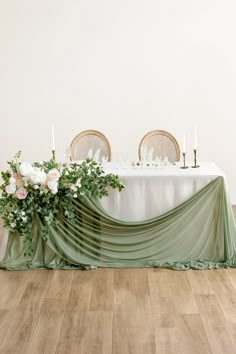 the table is set with white flowers and greenery