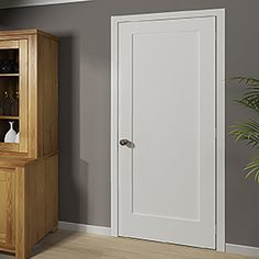 a wooden cabinet sitting in the corner of a room next to a potted plant