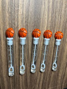 four plastic basketballs are in the shape of tubes on a wooden surface with metal handles