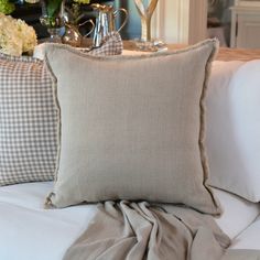 a bed with two pillows on top of it and flowers in vases behind them