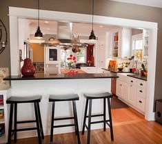 a kitchen with three stools in front of the island and an open floor plan