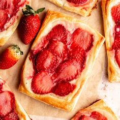 strawberry shortbreads on parchment paper with fresh strawberries in the middle and cut into squares