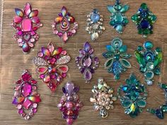 there are many different colored brooches on the wooden table, including pink and blue