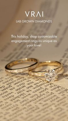 two gold wedding rings sitting on top of an open book with the words vrai written in