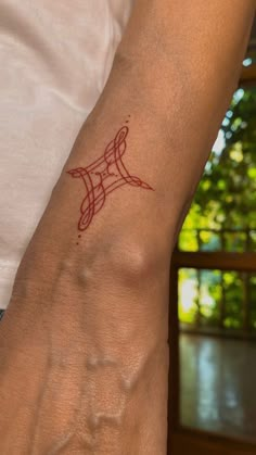 a person's arm with a tattoo on it that has a small red design