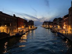 a canal at night with boats in the water and buildings on both sides that are lit up