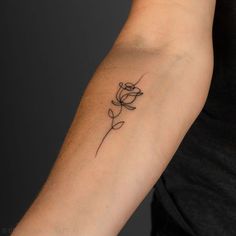 a woman's arm with a small flower tattoo on the left side of her arm