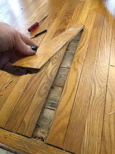 a person is holding a piece of wood in their hand while they are working on the floor