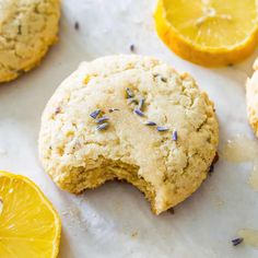 an orange and lavender cookies with one broken in half on a white surface next to sliced lemons