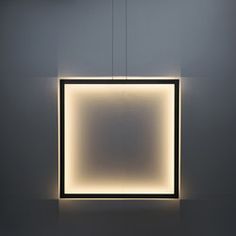 a square light hanging from the ceiling in a room with white walls and flooring