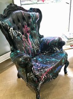 a black chair with colorful paint splattered on it's back and arms