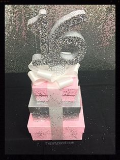 a pink and white gift box with a number six on it's top, sitting in front of a glitter background