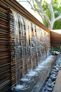 a water feature in the middle of a wooden decked area with rocks and plants