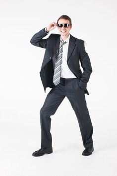 a man in a suit and tie posing for the camera with his hands on his hips