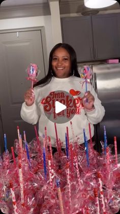 a woman standing in front of a table filled with pink lollipops and marshmallows