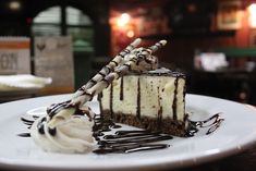 a piece of cake on a white plate with chocolate drizzle and whipped cream