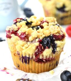 a muffin with blueberries and crumbled toppings sits on a table