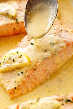 a spoon is being drizzled with cheese sauce on top of salmon patties