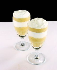 two glasses filled with dessert sitting on top of a table