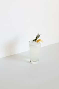 a glass filled with ice and lemon wedges on top of a white countertop