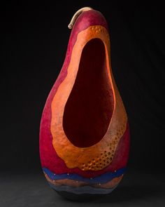 an orange and red vase sitting on top of a table