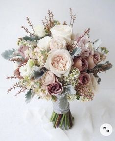 a bridal bouquet with pink and white flowers on a white tableclothed surface