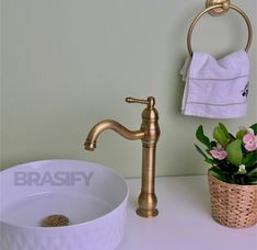 a bathroom sink with a gold faucet next to a white bowl filled with flowers