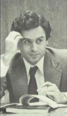 a man in a suit and tie sitting at a desk with an open book on it