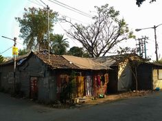 an old run down shack with clothes hanging on it's roof and trees in the background