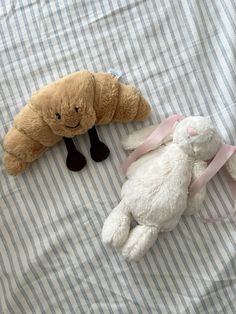 two stuffed animals laying next to each other on a bed