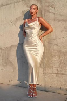 a woman in a white dress leaning against a wall