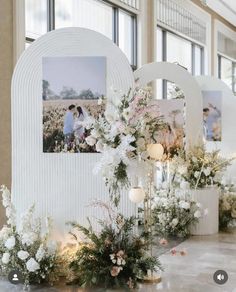 a couple kissing in front of an arch with flowers and candles on the floor next to them