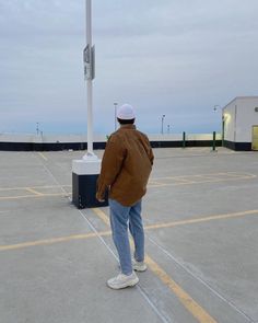 a man standing in an empty parking lot with his back to the camera and looking at something