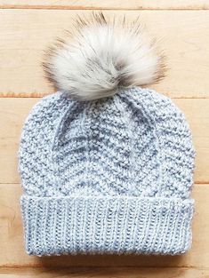 a knitted hat with a white and grey pom - pom on top