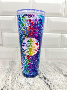 the starbucks cup is decorated with colorful glitters