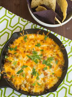 a skillet filled with cheese and tortilla chips next to a bowl of guacamole