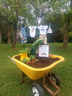 a yellow wheelbarrow filled with dirt and vegetables