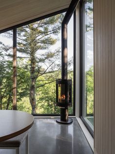 a room with large windows and a fire place in the corner near a dining table