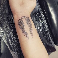 a person with a tattoo on their arm that has two angel wings and an halo